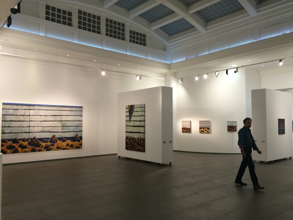The artist in the exhibition space, with "Falaise, Chaos de plage, Tryptique" (135 x 325 cm, Oil on Canvas, 2016) The artist in the exhibition space, with "Falaise, Chaos de plage, Tryptique" (135 x 325 cm, Oil on Canvas, 2016)