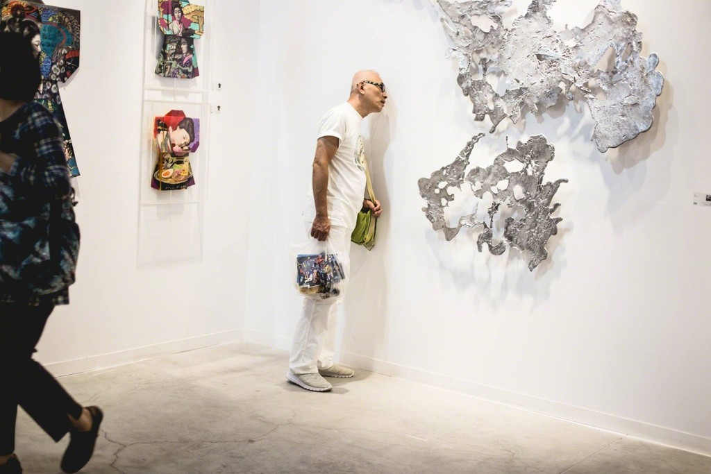 A visitor examines Jinggoy Buensuceso's melted aluminum piece, "Ink." A visitor examines Jinggoy Buensuceso's melted aluminum piece, "Ink."