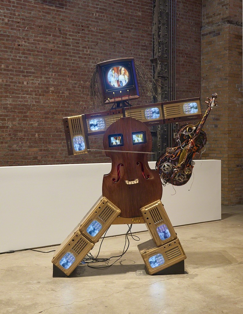 Nam June Paik, Charlotte Moorman II, 1995, installation view. Nine antique TV cabinets, two cellos, one 13-inch color TV, two 5-inch color TVs, eight 9-inch color TVs, and two- channel video. 92 x 68 x 24 inches (233.68 x 172.72 x 60.69 cm). The Rose Art Museum, Brandeis University, Waltham, MA; Hays Acquisition Fund. Photo: Kyle Knodell
Nam June Paik, Charlotte Moorman II, 1995, installation view. Nine antique TV cabinets, two cellos, one 13-inch color TV, two 5-inch color TVs, eight 9-inch color TVs, and two- channel video. 92 x 68 x 24 inches (233.68 x 172.72 x 60.69 cm). The Rose Art Museum, Brandeis University, Waltham, MA; Hays Acquisition Fund. Photo: Kyle Knodell
