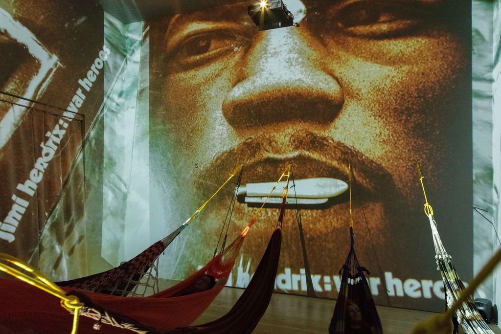 Hélio Oiticica. Installation view. CC5 Hendrix-War,1973.Thirty-three 35mm color slides transferred to digital slideshow, sound, and hammocks. Site Specific Collections of César and Claudio Oiticica and Neville D’Almeida. Whitney Museum of American Art, New York, N.Y. Photograph by Oto Gillen Hélio Oiticica. Installation view. CC5 Hendrix-War,1973.Thirty-three 35mm color slides transferred to digital slideshow, sound, and hammocks. Site Specific Collections of César and Claudio Oiticica and Neville D’Almeida. Whitney Museum of American Art, New York, N.Y. Photograph by Oto Gillen