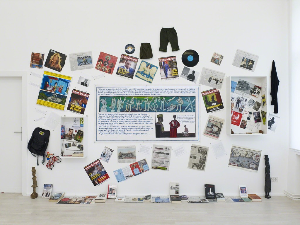 Georges Adéagbo „Les artistes et l‘écriture“..!, 2014, Mixed Media, wall 1: 320 (h) x 430 (w) x 22 (d) cm, wall 2: 310 (h) x 610 (w) x 19 (d) cm, wall 3: 290 (h) x 440 (w) x 22 (d) cm, floor: 285 x 140 x 64 cm, Installation view of „Les artistes et l‘écriture“..! at Gallery Wien Lukatsch, Berlin 2014, Courtesy: Gallery Wien Lukatsch, Berlin, Photos: Nick Ash Georges Adéagbo „Les artistes et l‘écriture“..!, 2014, Mixed Media, wall 1: 320 (h) x 430 (w) x 22 (d) cm, wall 2: 310 (h) x 610 (w) x 19 (d) cm, wall 3: 290 (h) x 440 (w) x 22 (d) cm, floor: 285 x 140 x 64 cm, Installation view of „Les artistes et l‘écriture“..! at Gallery Wien Lukatsch, Berlin 2014, Courtesy: Gallery Wien Lukatsch, Berlin, Photos: Nick Ash
